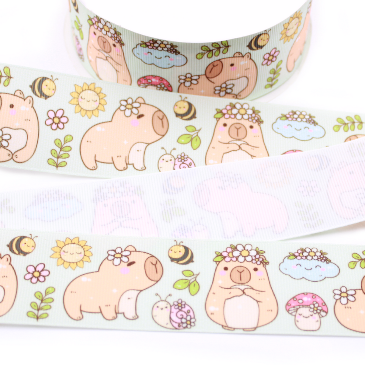 Kawaii Capybara printed grosgrain ribbon with cute capybaras, flowers, bees, mushrooms and snails on a pale mint background.