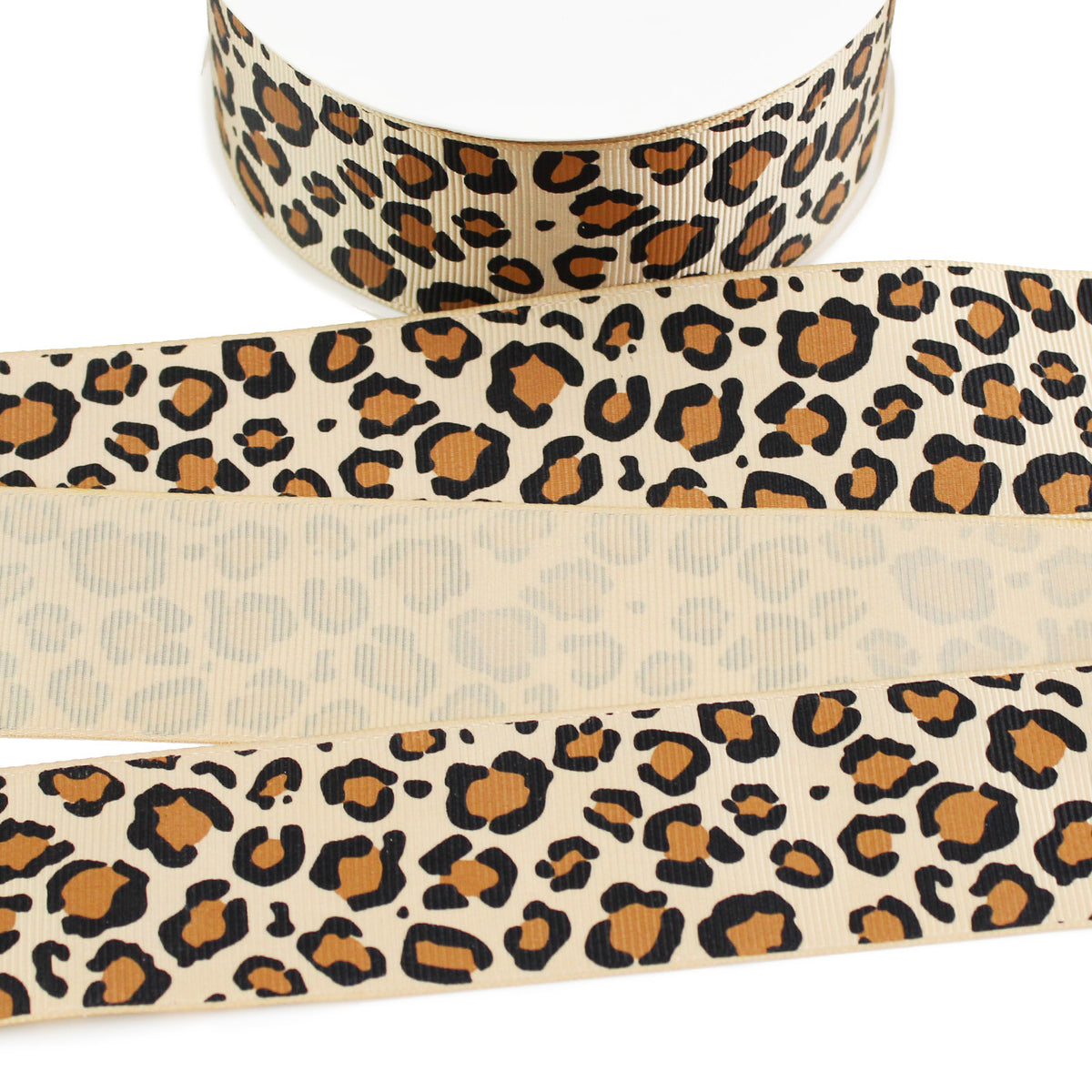 Tan grosgrain ribbon featuring a classic leopard animal print pattern with irregular black spots and warm brown centers, shown on a spool with front and back sides visible.