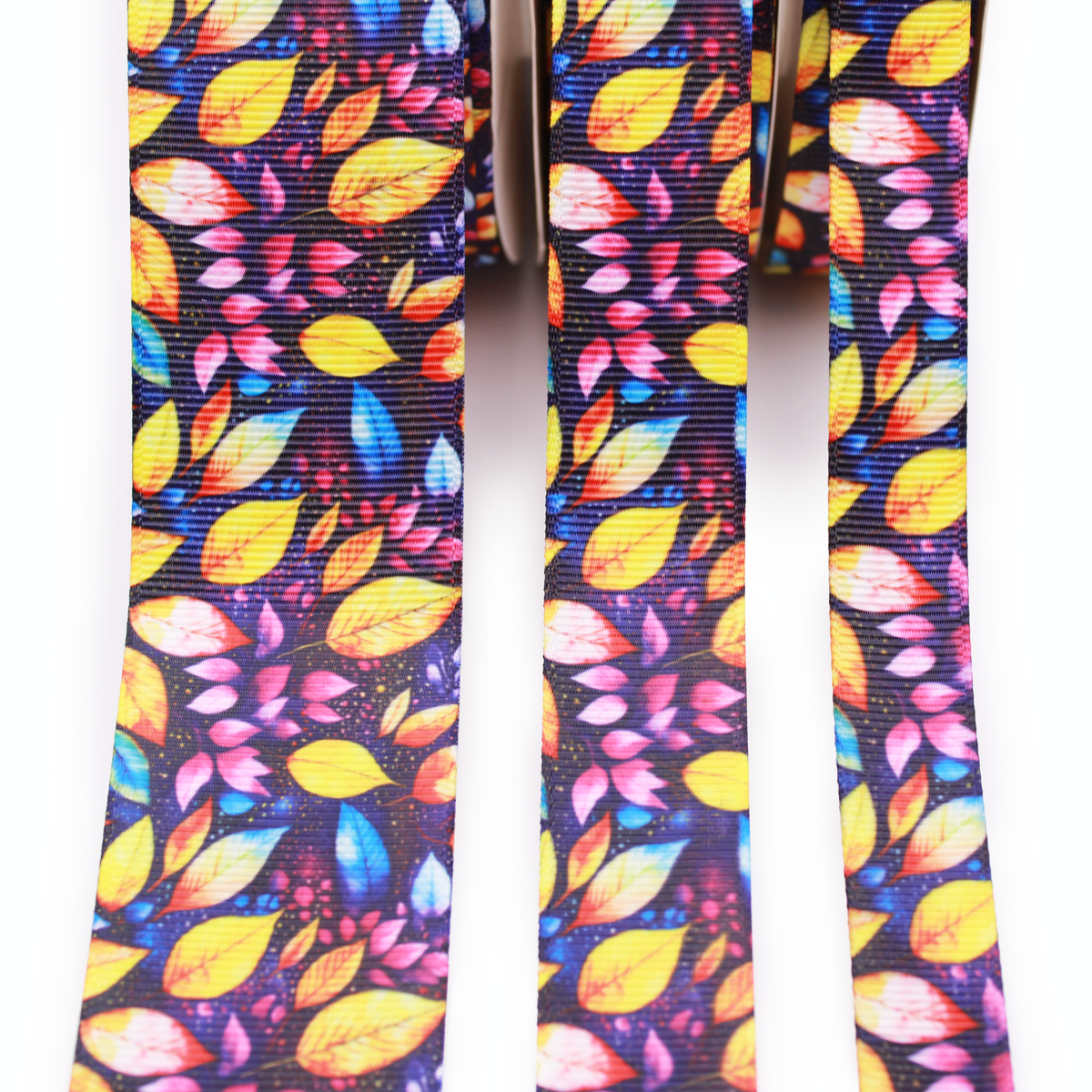 Colorful fall leaves printed grosgrain ribbon with yellow, orange, pink and blue leaves on a dark background.