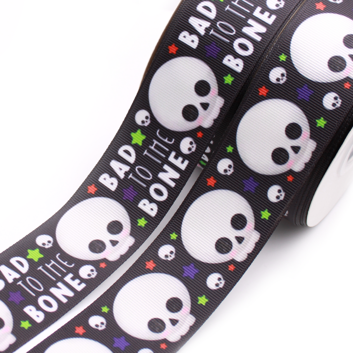 Bad to the Bone printed grosgrain ribbon with cute white skulls, colorful stars and white lettering on a black background.