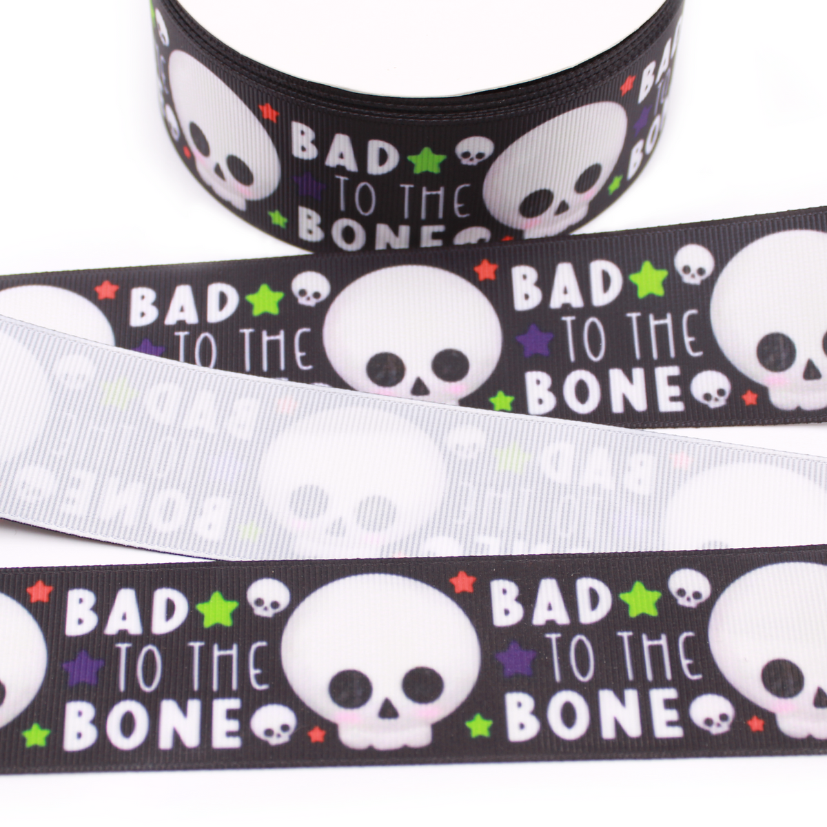 Bad to the Bone printed grosgrain ribbon with cute white skulls, colorful stars and white lettering on a black background.
