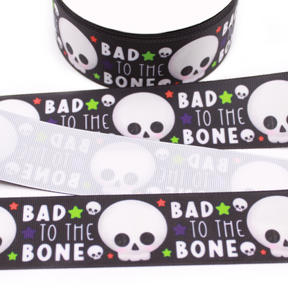Bad to the Bone printed grosgrain ribbon with cute white skulls, colorful stars and white lettering on a black background.