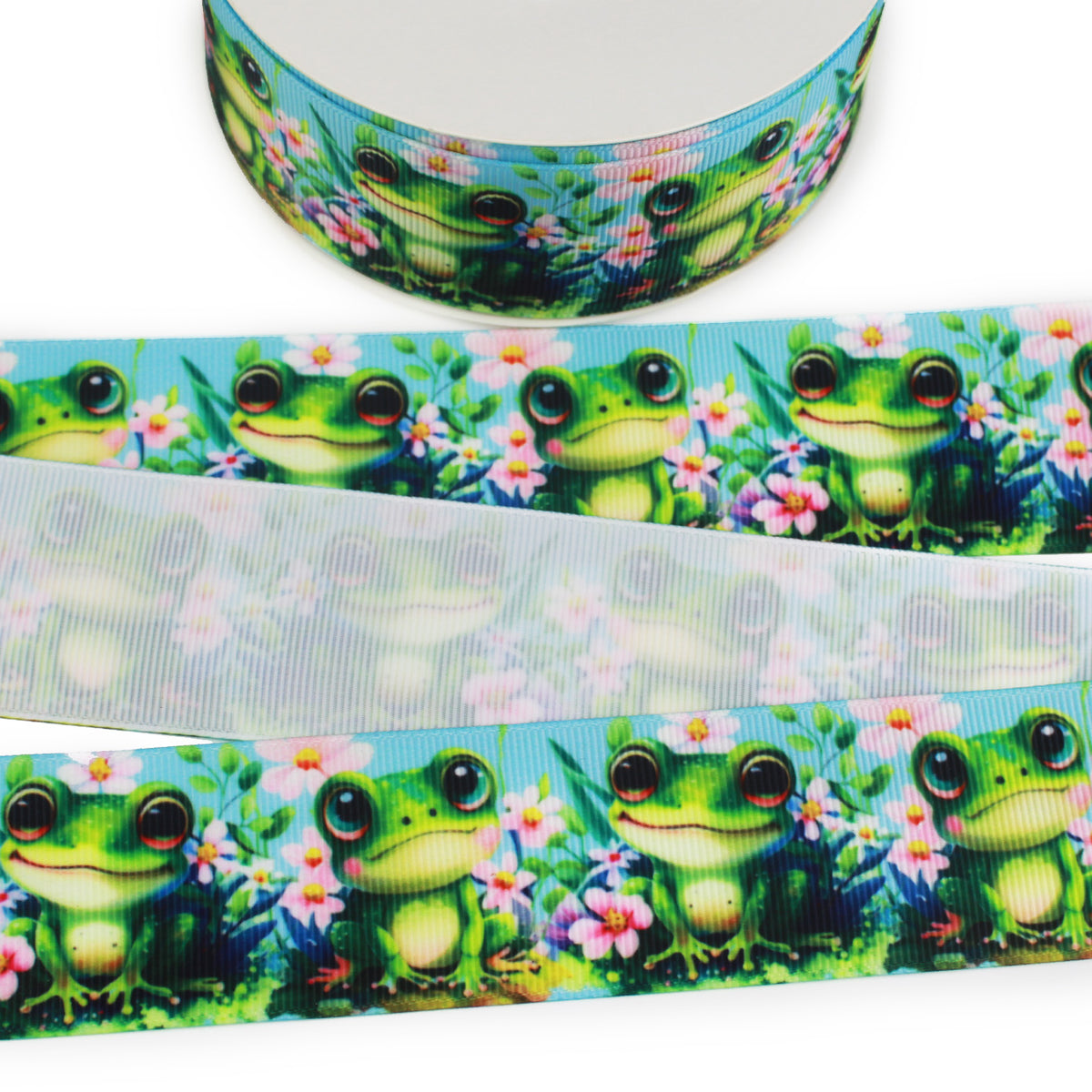 Printed grosgrain ribbon featuring bright green frogs with large eyes surrounded by pink flowers and lush greenery on a blue background.