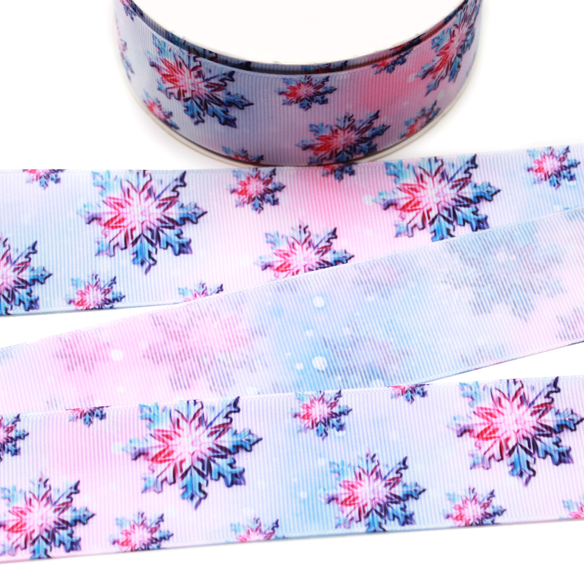 Pink and blue snowflake printed grosgrain ribbon with layered pink, blue and navy snowflakes on a soft watercolor-style winter background.