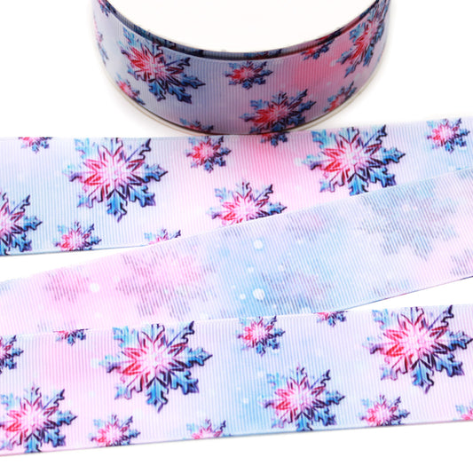 Pink and blue snowflake printed grosgrain ribbon with layered pink, blue and navy snowflakes on a soft watercolor-style winter background.