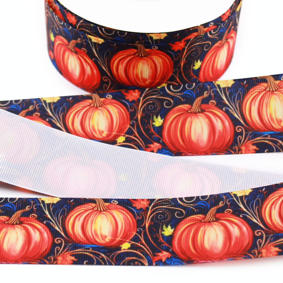 Pumpkin printed grosgrain ribbon with orange pumpkins, autumn leaves and swirling vines on a dark navy background.